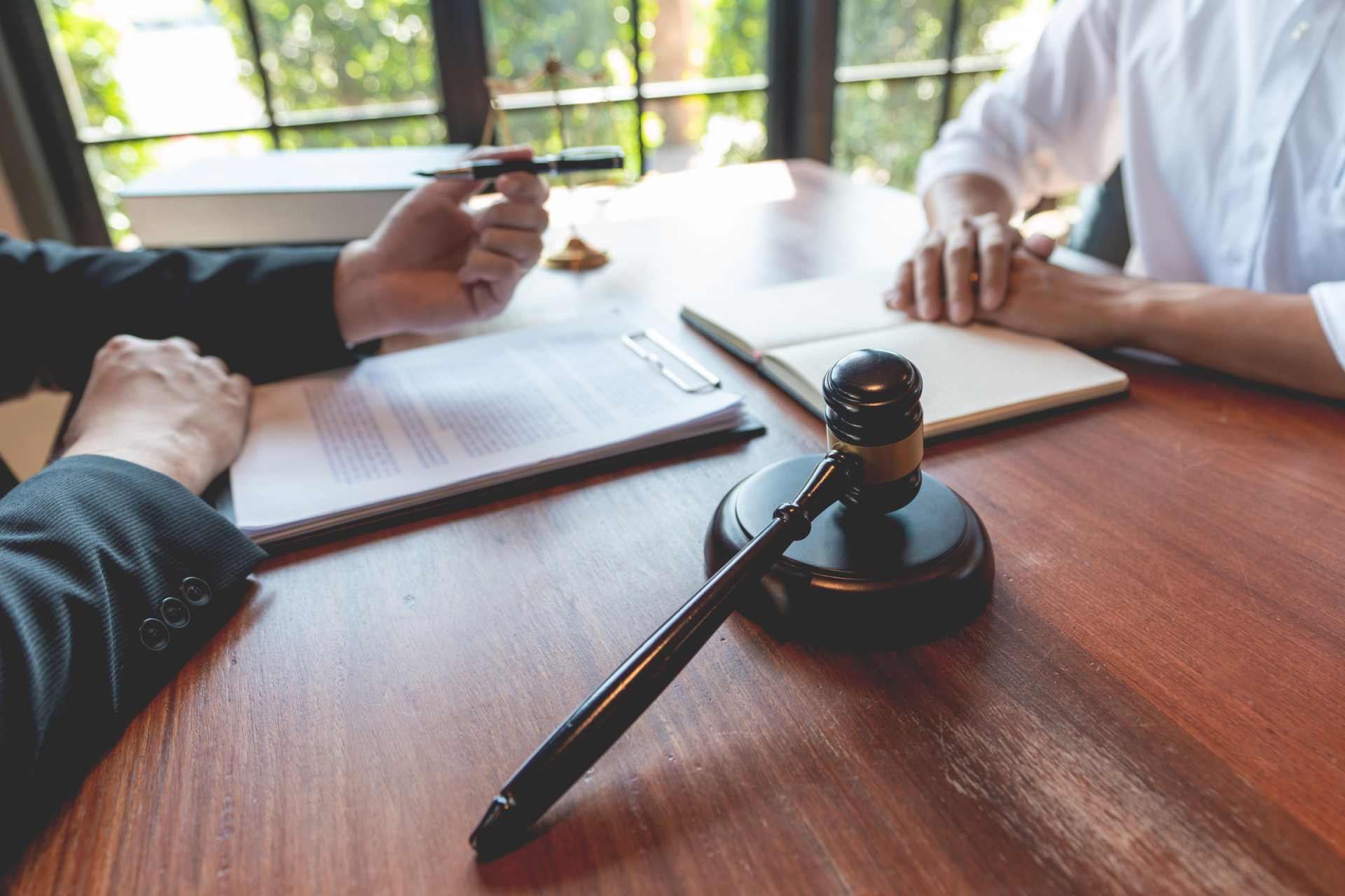 A lawyer offering a pen to a client to sign and settle a court case.