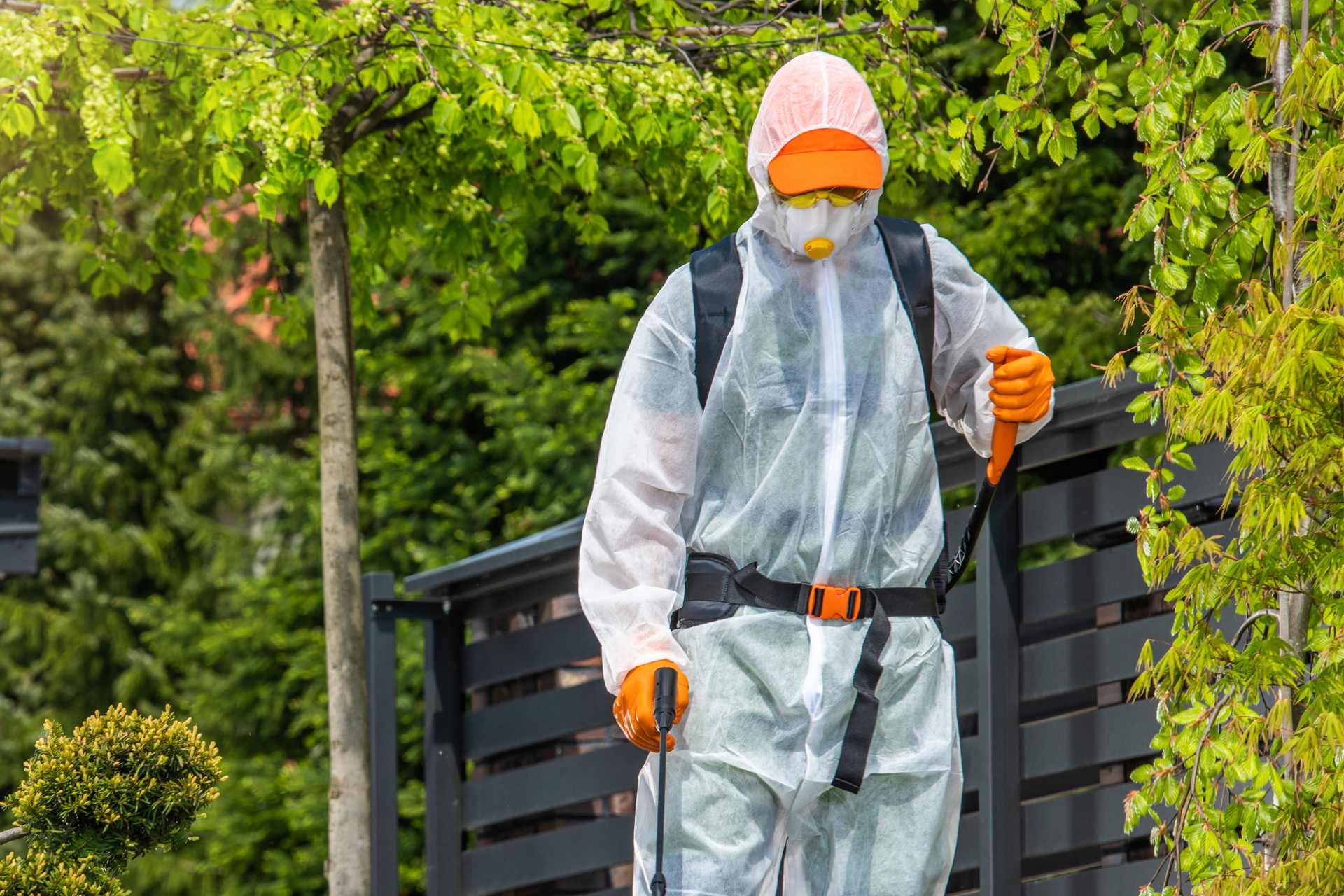 A Professional Gardener Working in Protection Suite Spraying Glyphosate on a driveway.