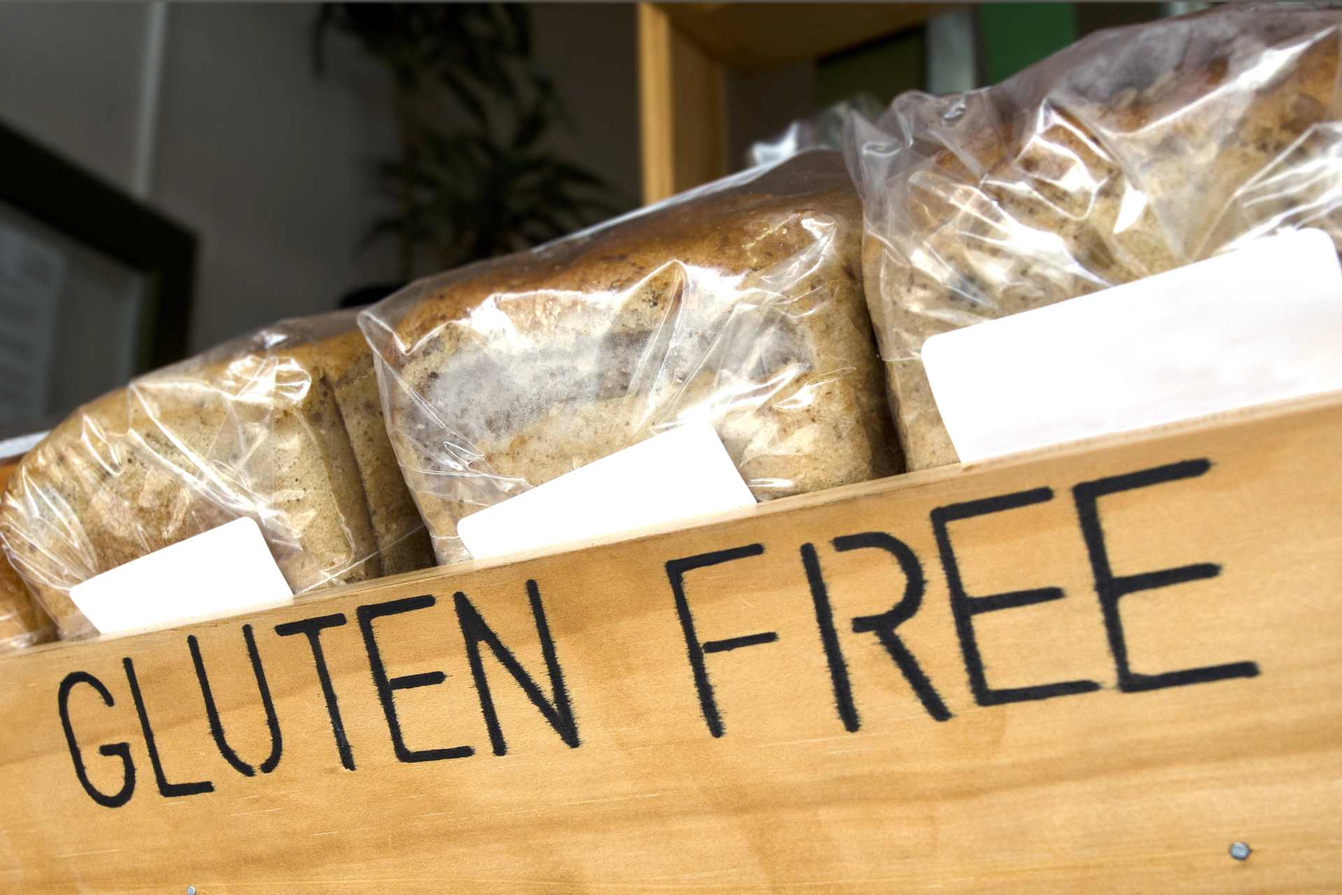 Three loaves of gluten-free bread in a rustic wooden box, highlighting the irony that gluten-free products may still contain glyphosate residues despite their health-focused image.