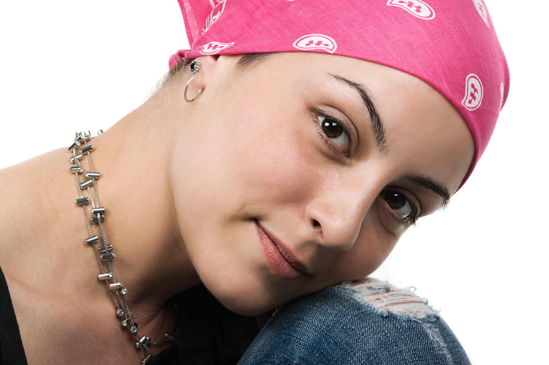 Close up of a female cancer survivor wearing a pink head scarf with her head resting on her knee.