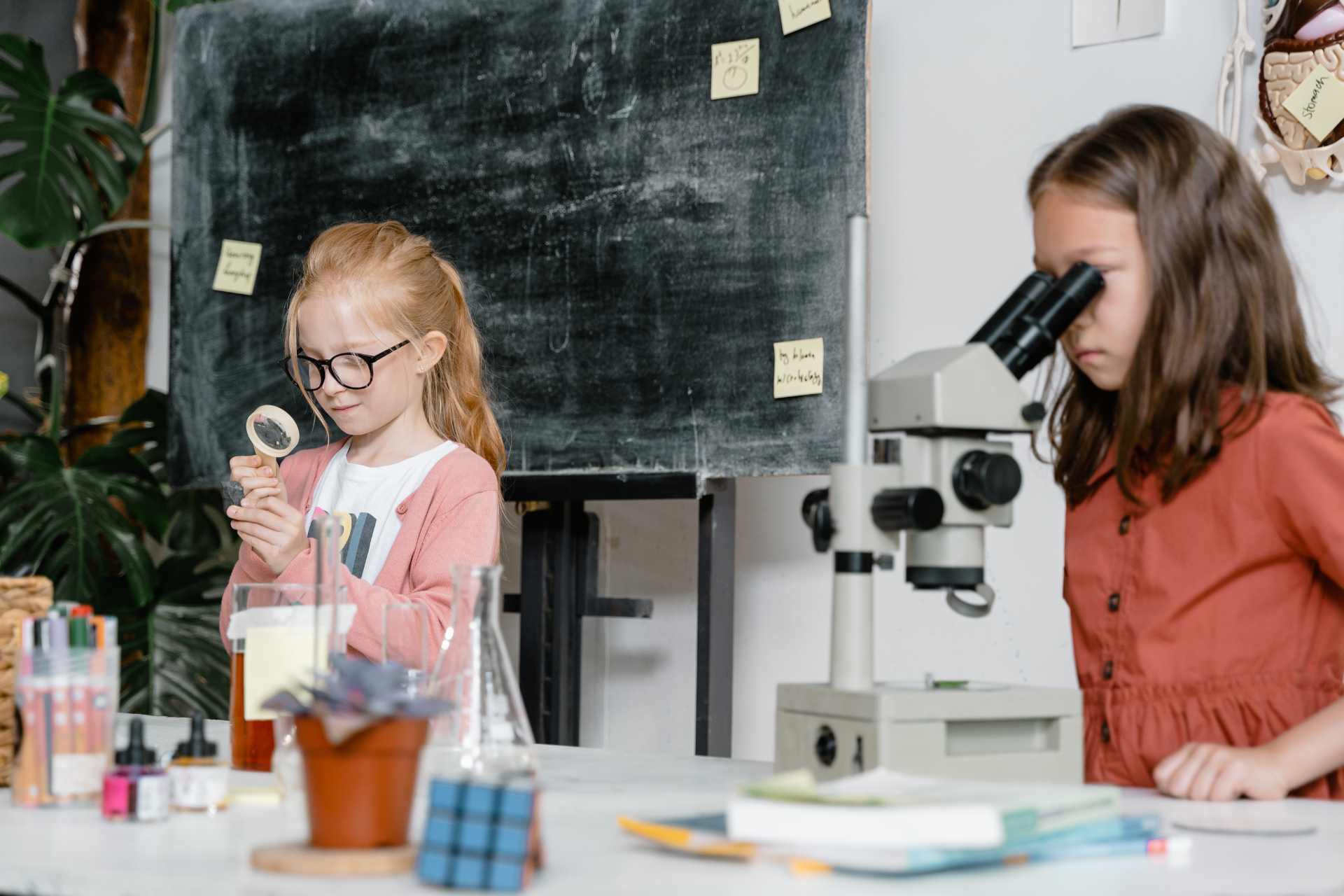 Two young girls playing in a lab setting, using lab equipment — a tongue-in-cheek visual twist on the question: “Safe… according to whom?
