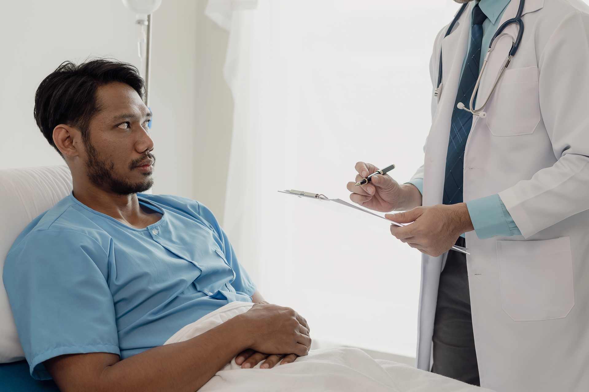 Doctor speaking with a male patient in a hospital bed, discussing health concerns — representing the challenges of identifying glyphosate-related illness in clinical settings.
