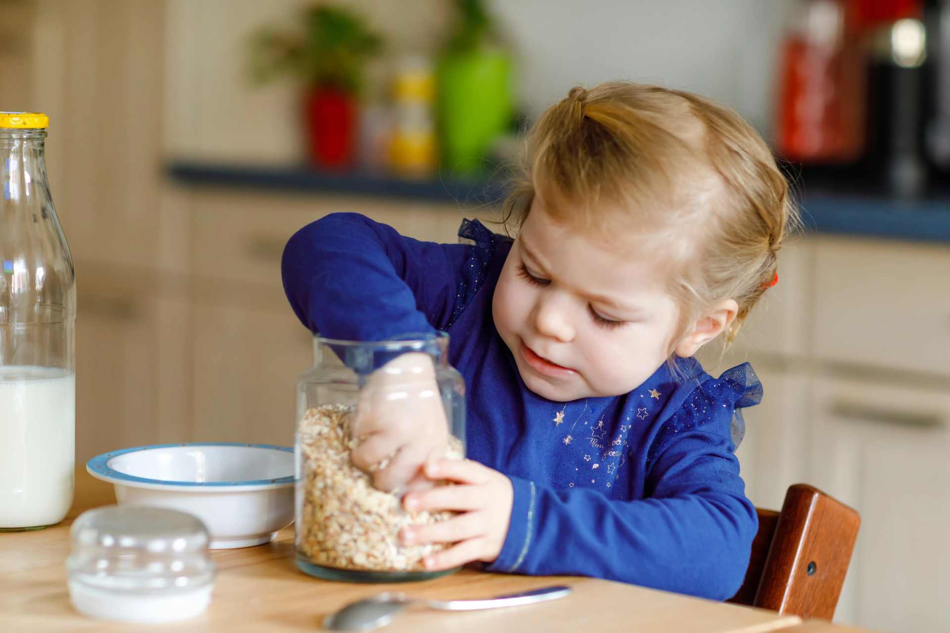 Young girl reaching into a cereal jar, helping herself to breakfast — a reminder of how everyday foods impact children.