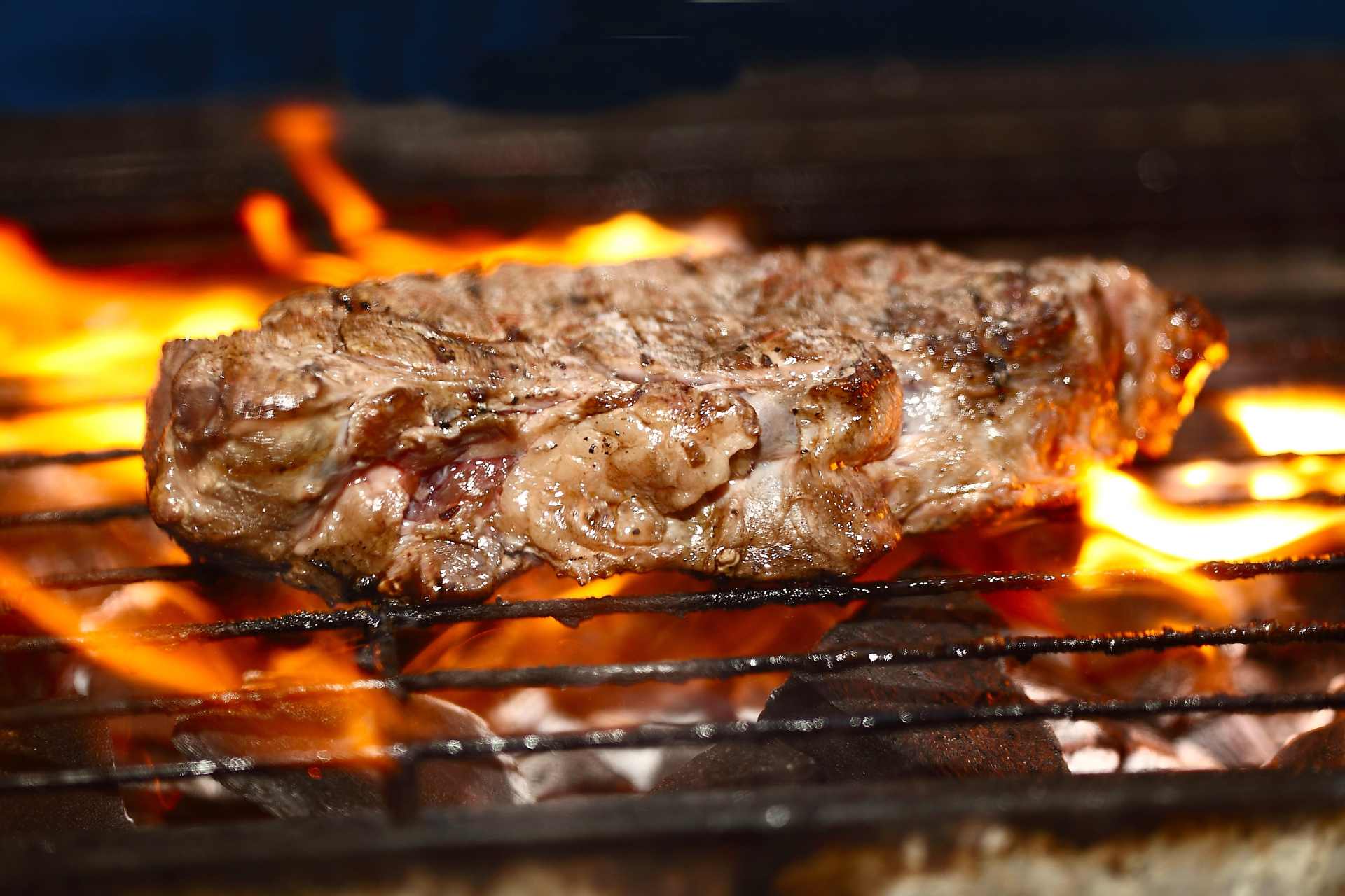 Flame-grilled steak sizzling over open flames — red meat is often cited alongside glyphosate as a 'probable carcinogen,' but the comparison obscures key differences.