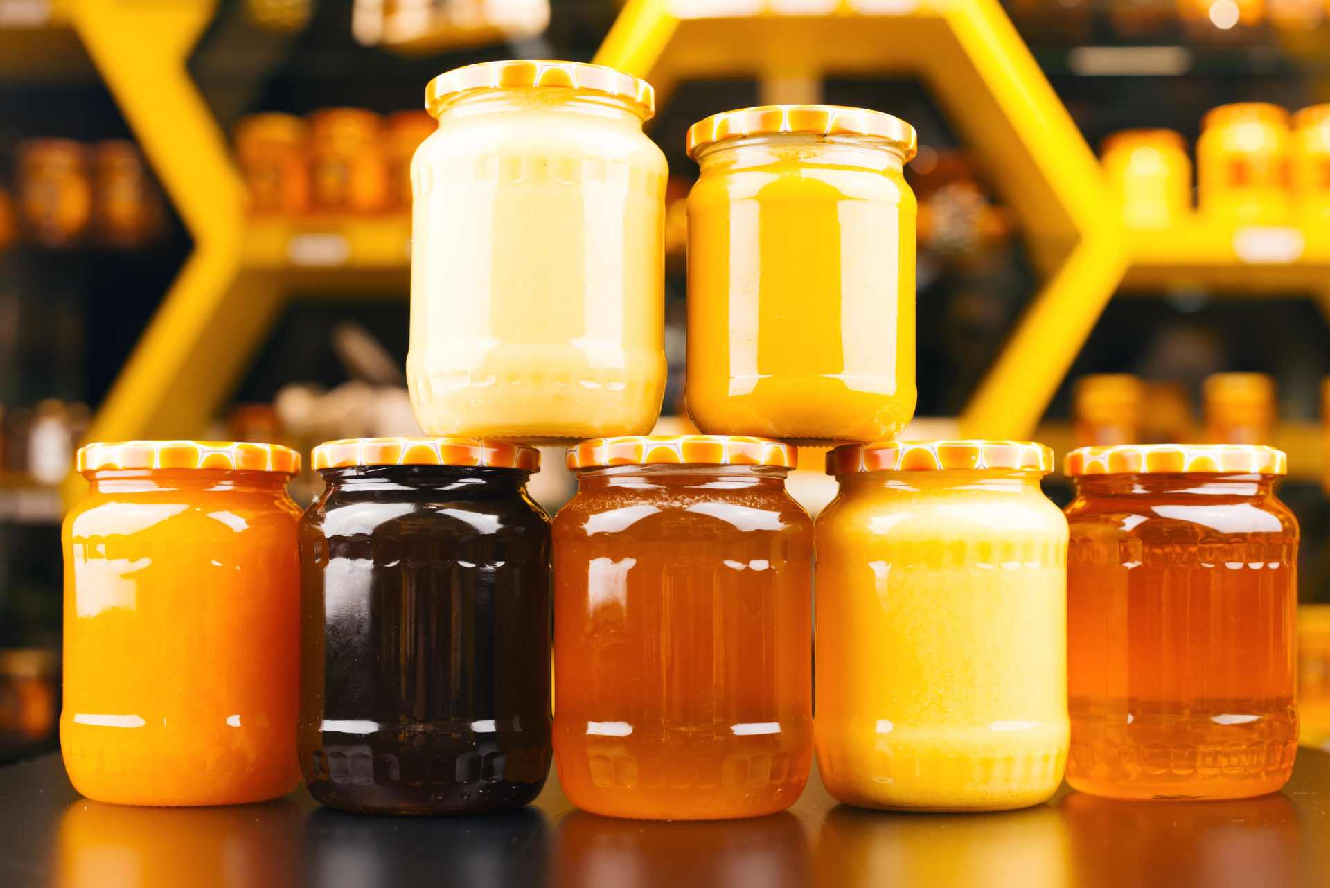 A variety of honey jars in different shapes and sizes, representing New Zealand brands sold for wellness and purity.