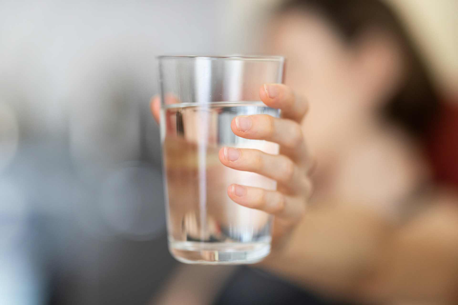 Close-up of a hand holding a clear glass of water — referencing the common claim that “even water is toxic.”