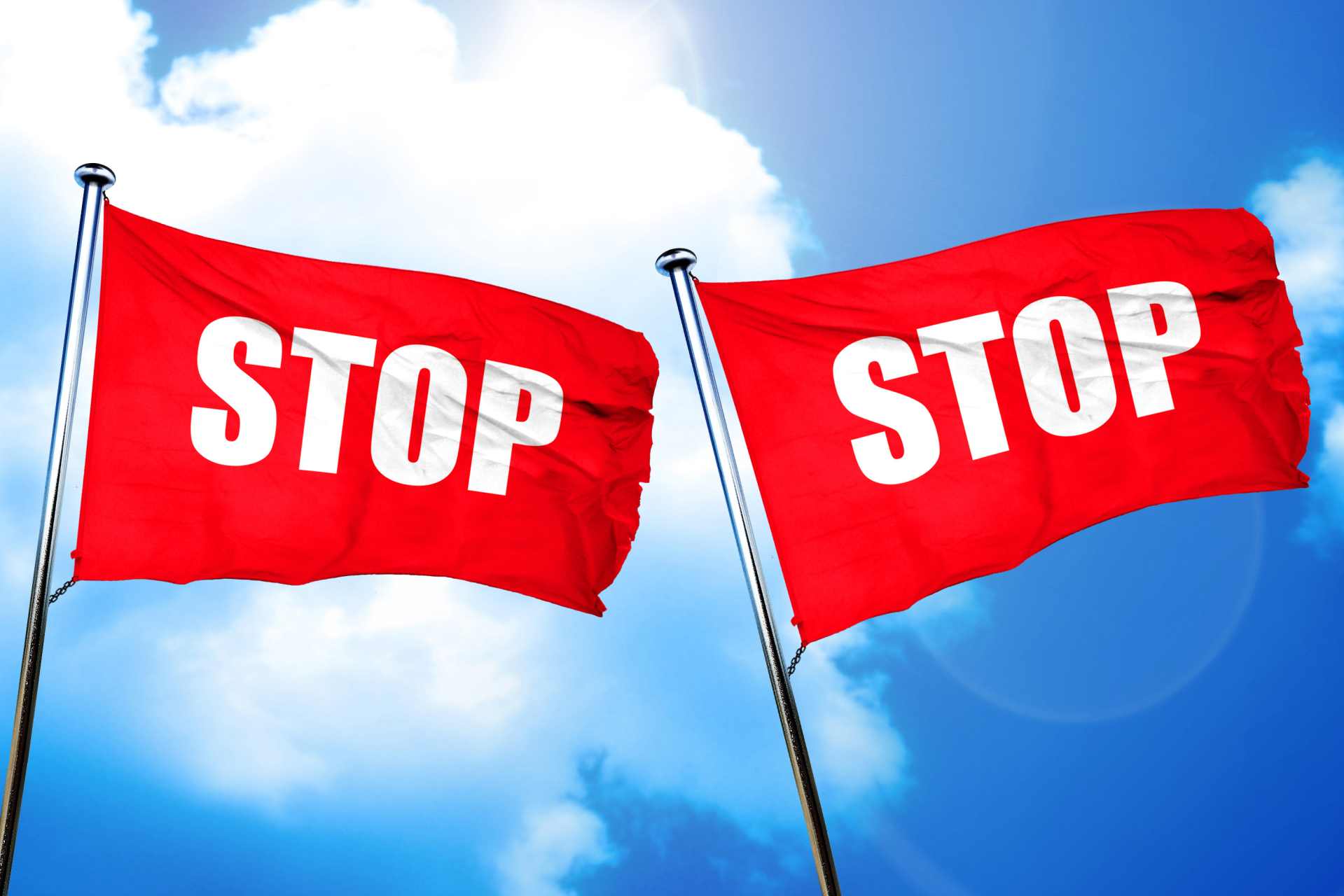 Two red flags with the word “STOP” printed on them flap in the wind, symbolizing ignored warnings about glyphosate’s health risks.