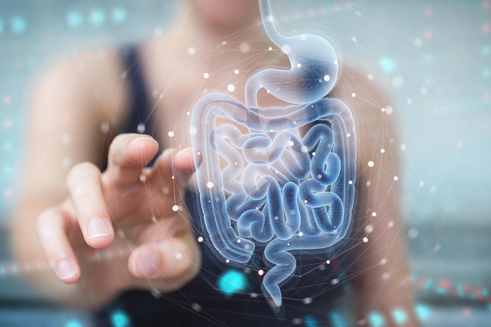 Woman interacting with a digital x-ray hologram of the human digestive system, highlighting the intestines. The futuristic interface suggests gut microbiome analysis or metabolic health diagnostics.