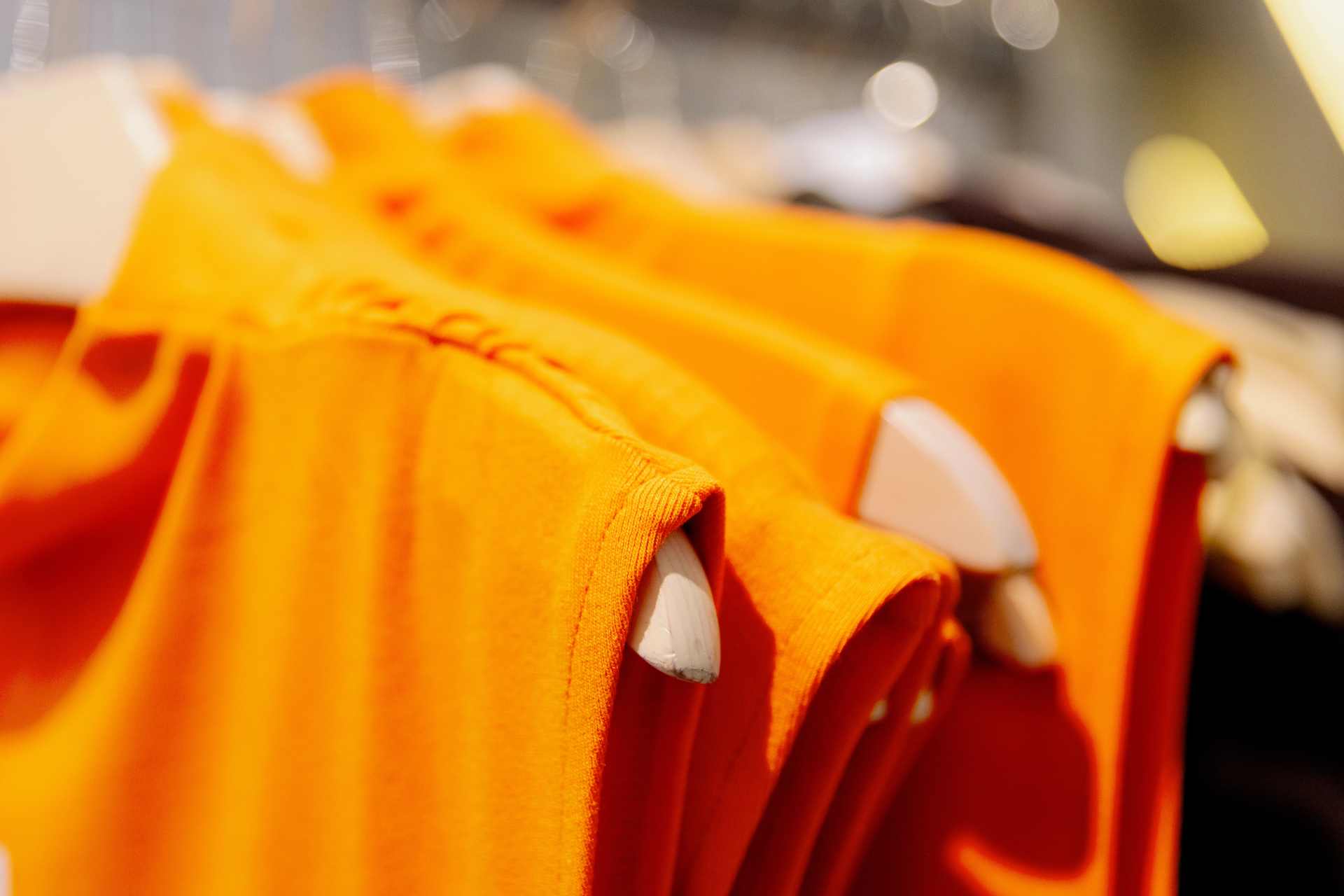 Close-up of a rack of orange cotton dresses, highlighting the fabric texture and vibrant color — a reminder that what we wear could carry hidden chemical residues like glyphosate.