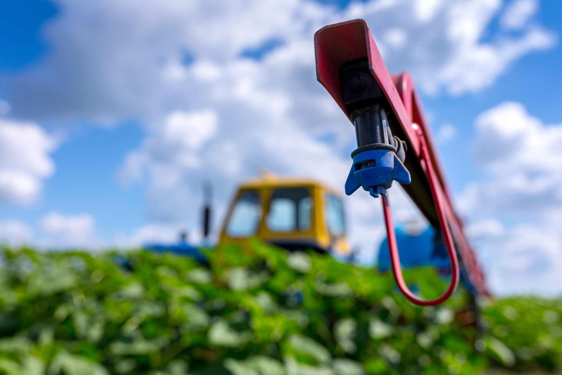 Close-up of a tractor spray boom applying herbicide over a crop in New Zealand, symbolising concerns about delayed glyphosate reassessment.
