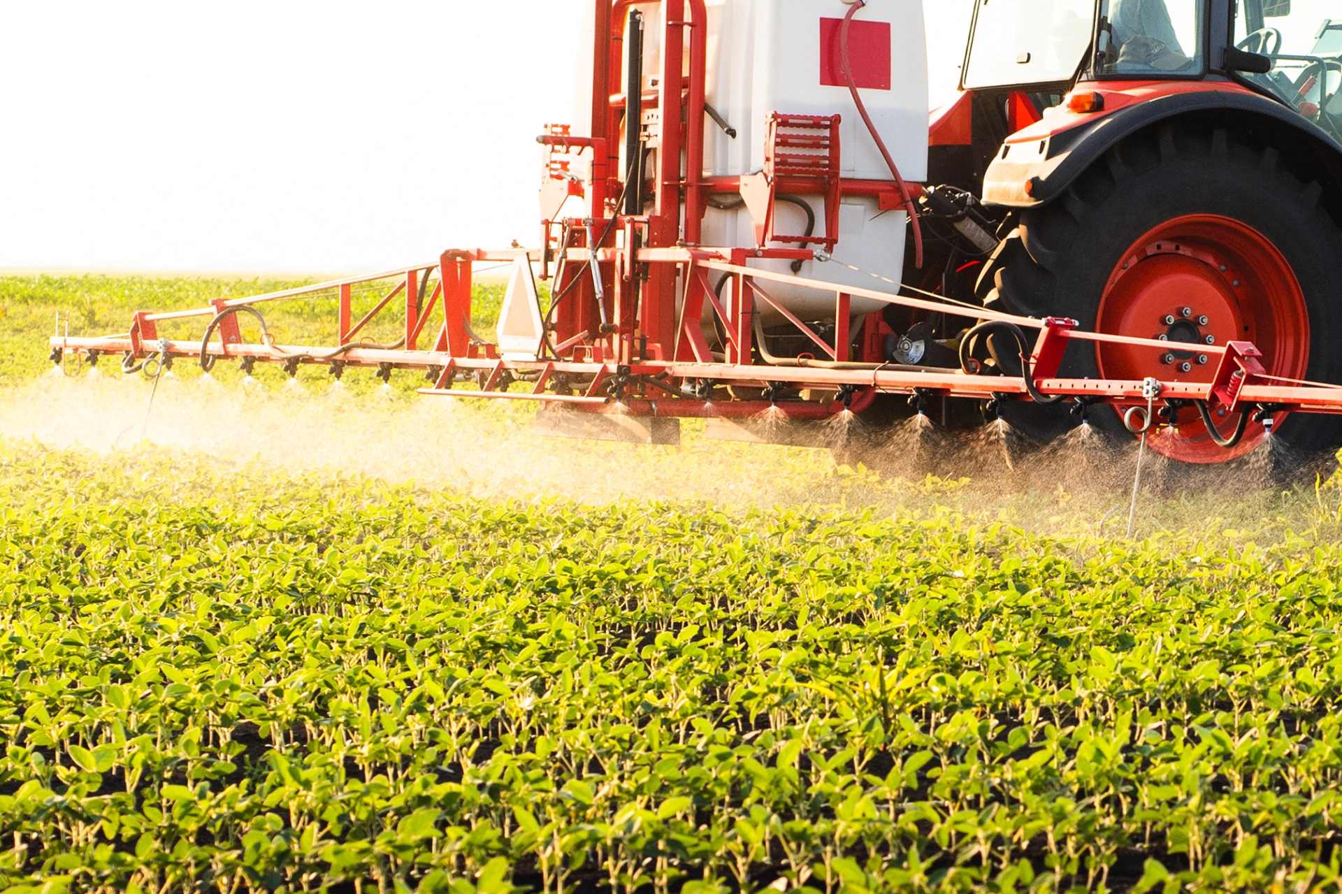 Close-up of a tractor boom spraying glyphosate herbicide across a field — symbolising industrial-scale dependence on chemical weed control.