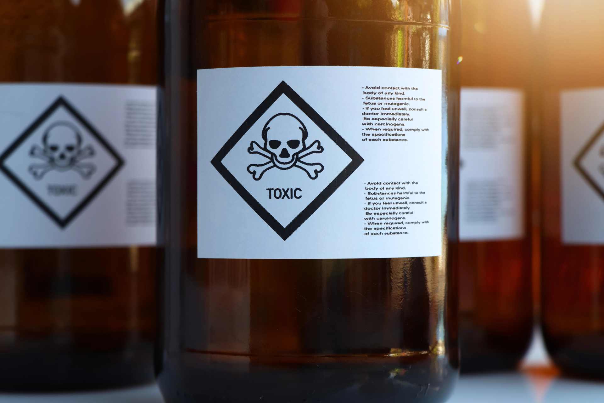 Close-up of unmarked chemical containers displaying a bold “Toxic” warning label and safety instructions, symbolising the hidden hazards in pesticide formulations like Roundup.