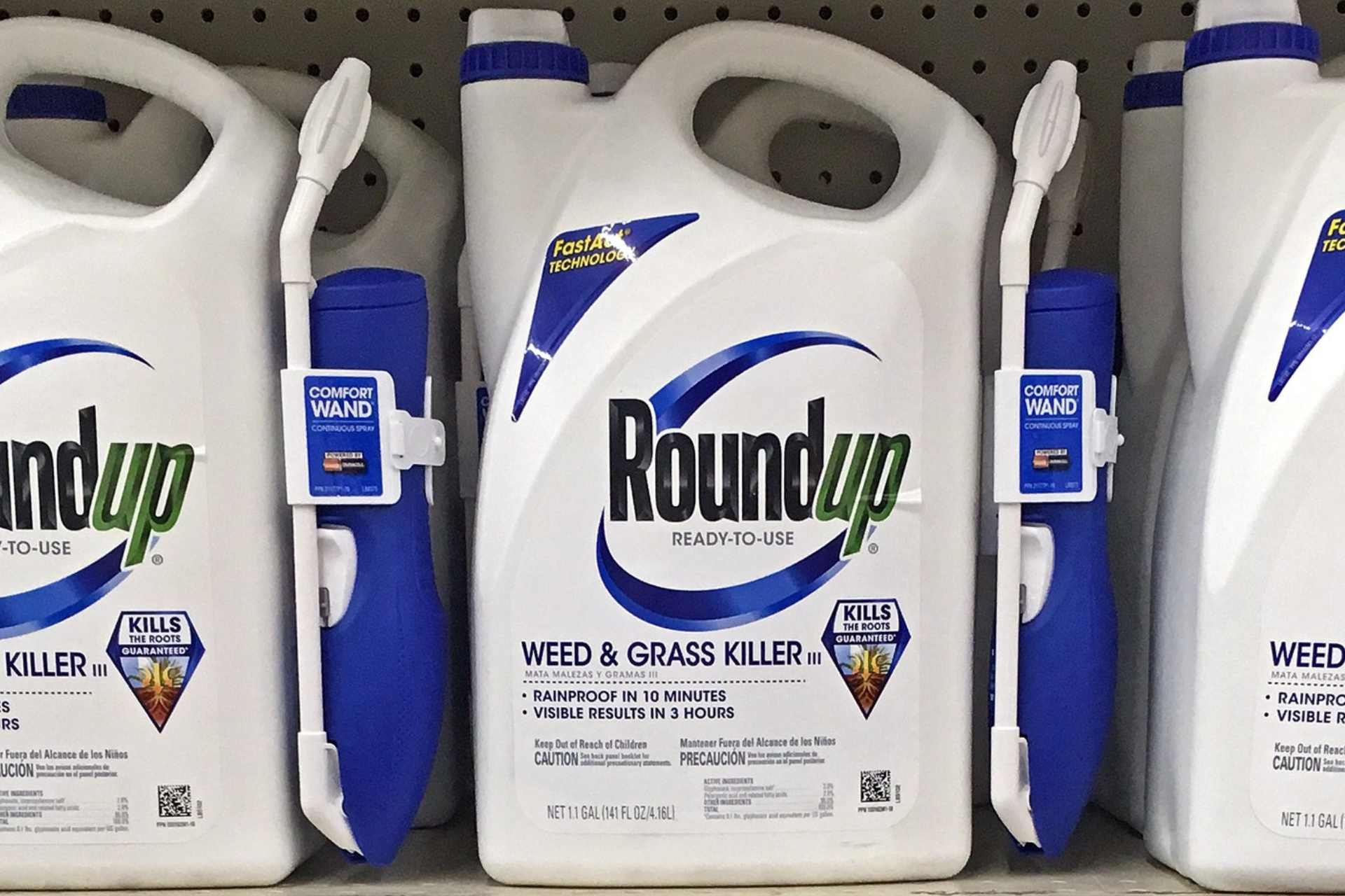 Close-up photograph of a Roundup retail weedkiller bottle on a store shelf, showing the product label clearly.