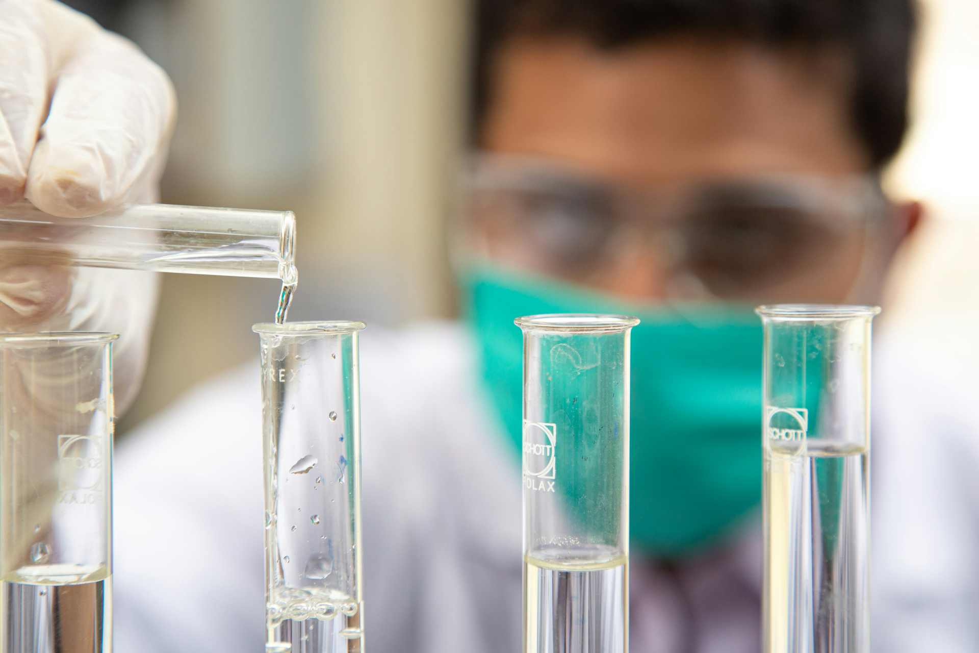 Laboratory technician filling test tubes with clear liquid as part of environmental screening tests