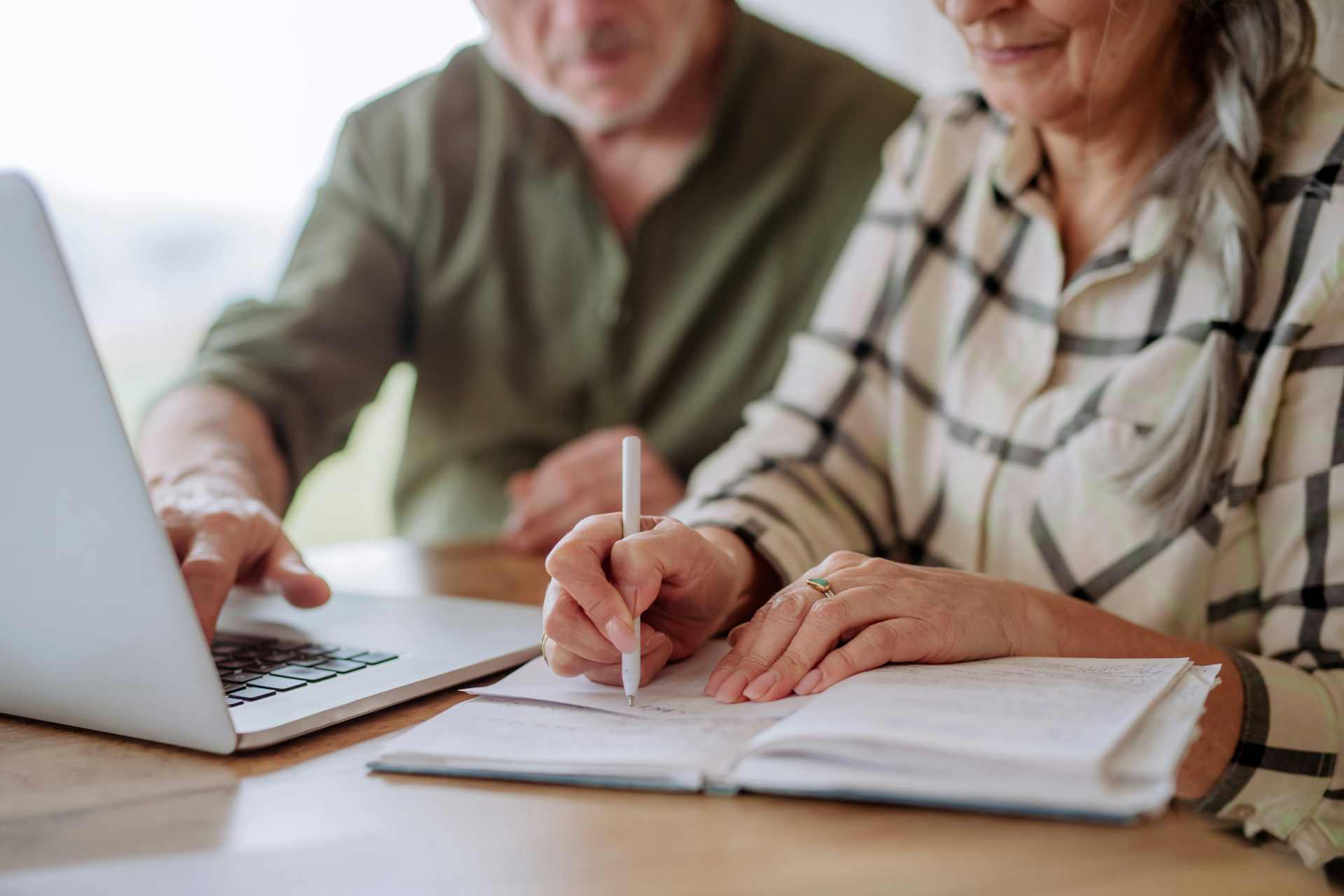 Man and woman reviewing information on a laptop and taking notes, representing a council information request process under LGOIMA in New Zealand