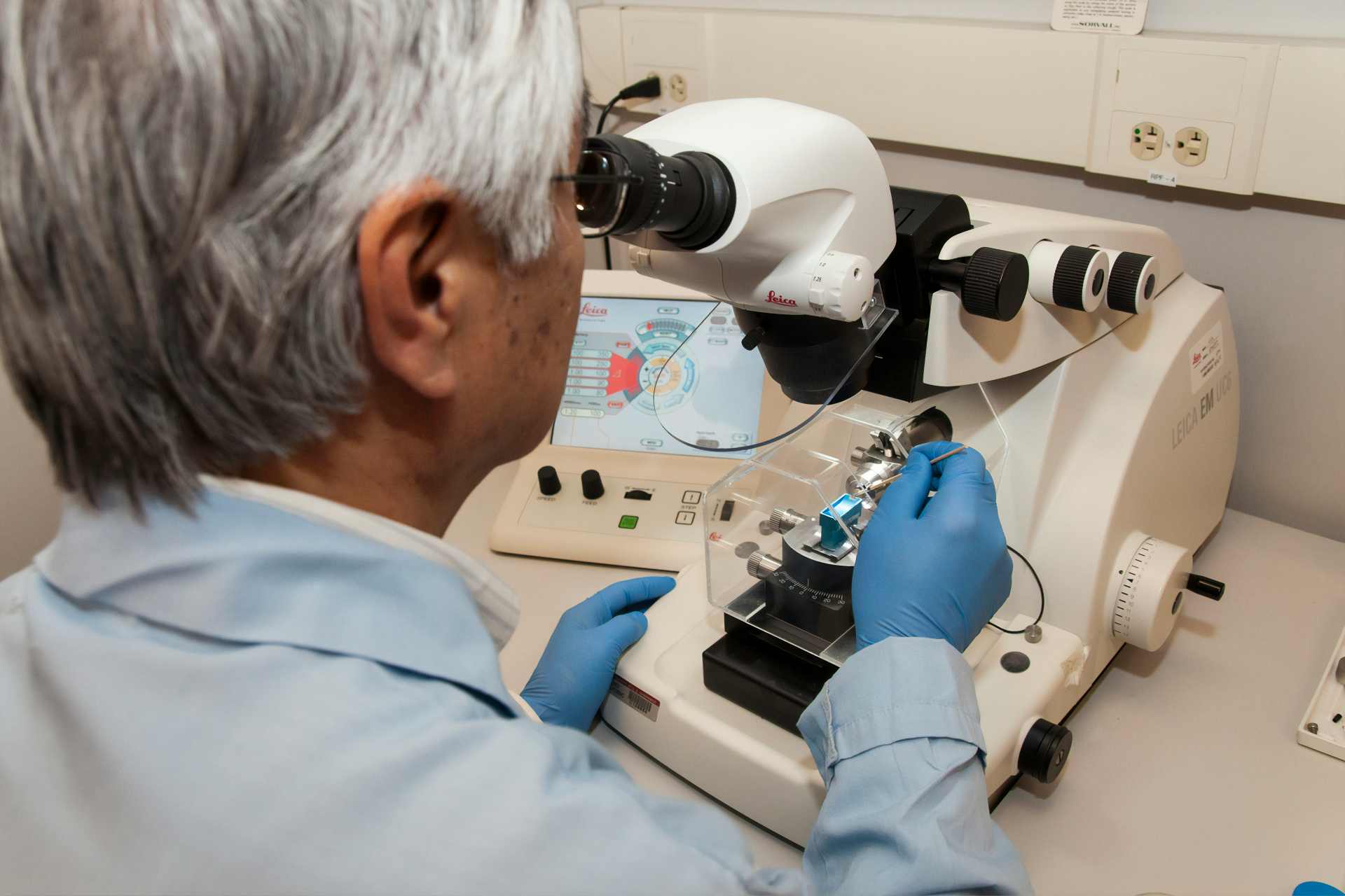 Laboratory technician using a microtome machine during scientific research into cellular and biological tissue analysis related to oxidative stress and long-term chemical exposure.