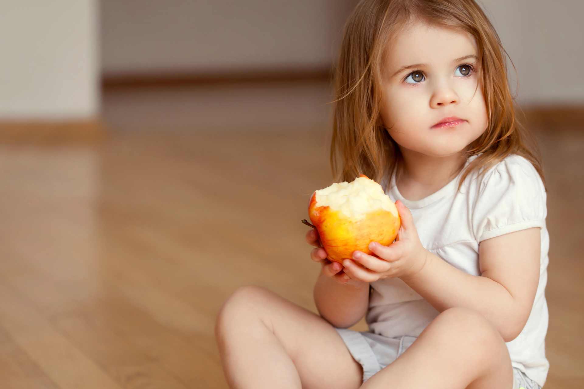 Young girl eating an apple while reflecting growing public questions around pesticide residue limits and chemical safety