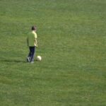 A school boy playing soccer on a school sports field, highlighting growing public questions around herbicide spraying, glyphosate use, and chemical exposure in environments used daily by children.
