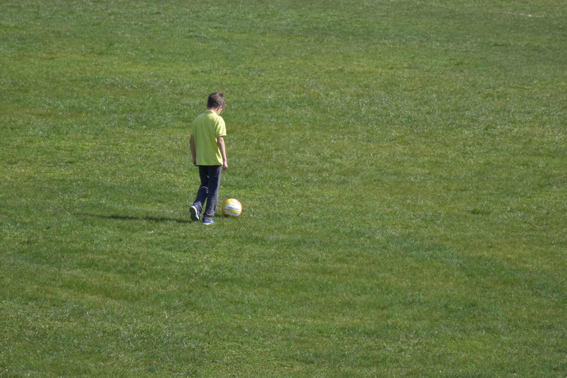 A school boy playing soccer on a school sports field, highlighting growing public questions around herbicide spraying, glyphosate use, and chemical exposure in environments used daily by children.