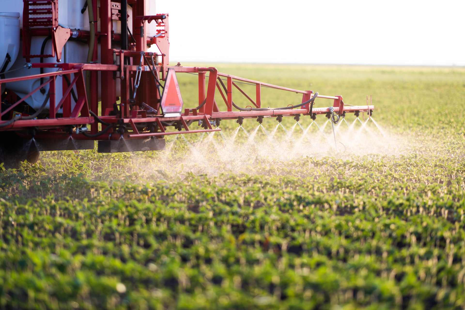 Tractor spraying herbicide across a large agricultural field, reflecting growing concerns about herbicide resistance and long-term reliance on chemical weed control systems.