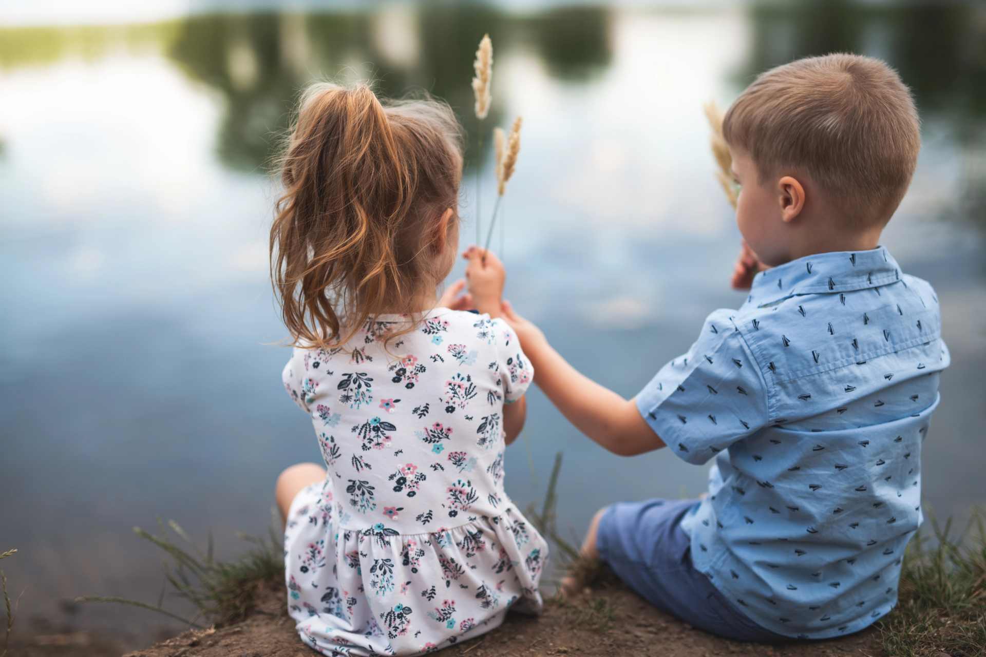 Happy young boy and girl sitting beside a lake, symbolising children's health and the importance of understanding environmental exposures such as glyphosate.
