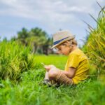 Young boy sitting in grass beside a crop field, representing questions about early-life glyphosate exposure and possible long-term effects.