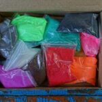 Plastic bags of brightly coloured children’s sand in an open cardboard box, illustrating New Zealand’s proposed precautionary safety measures for sand products.