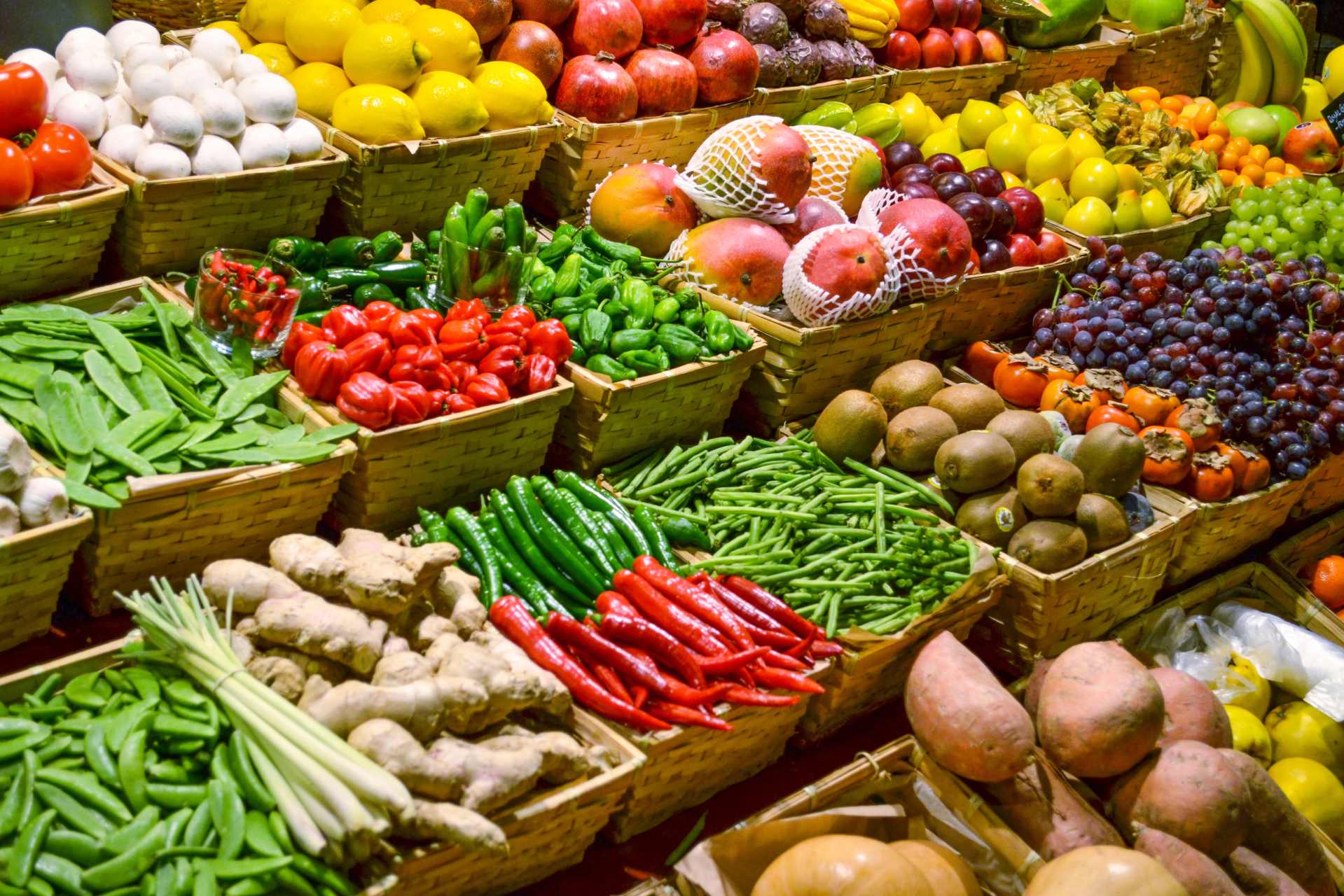 Colourful display of fresh fruits and vegetables arranged for sale at a produce market.